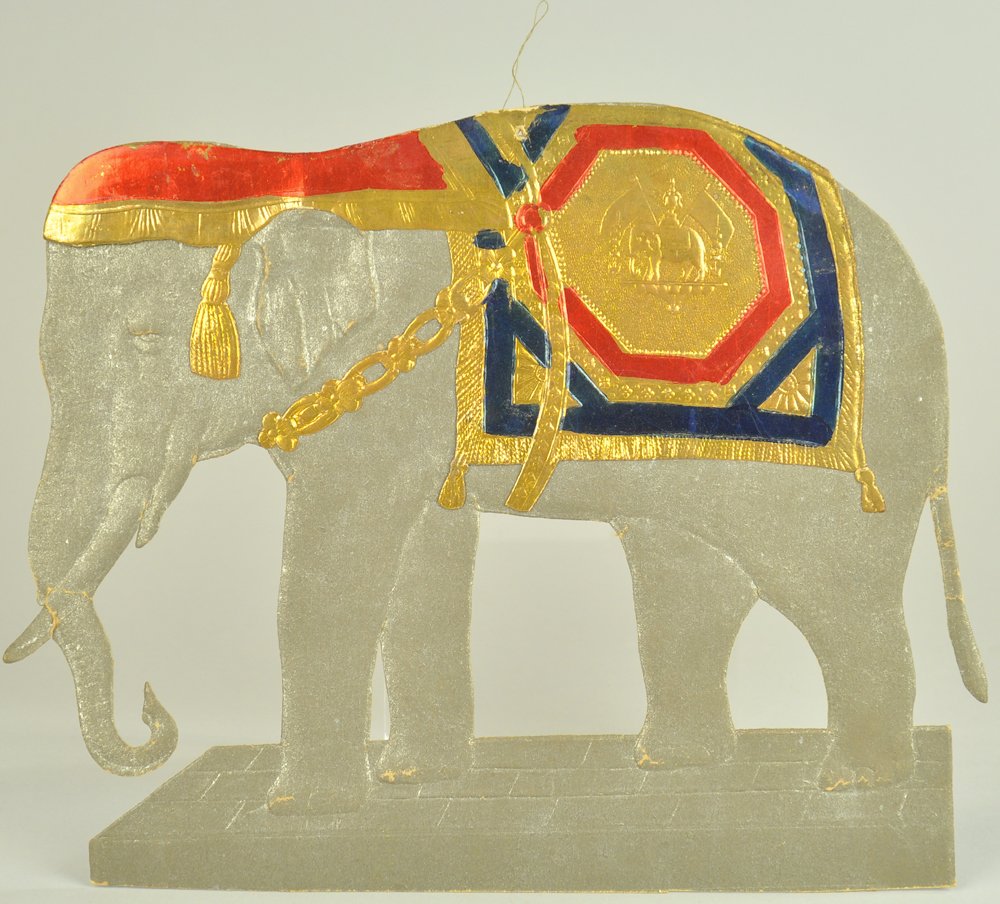 LARGE GERMAN DRESDEN GREY ELEPHANT: Pressed and embossed flat Dresden of an elephant with red, blue, and gold trim, strong colors. 8" l. Ex. Tom Fox Collection.
