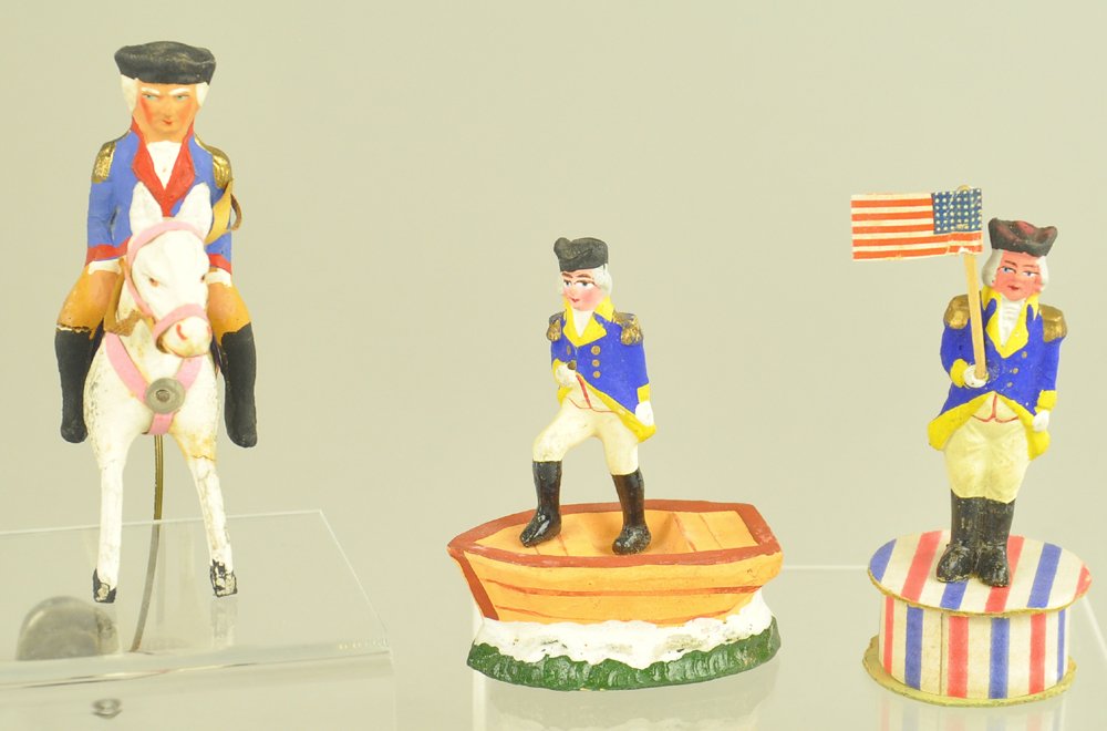 THREE GEORGE WASHINGTON FIGURALS: Germany, George Washington on a horse counter balance toy, in a boat standing, and on a red, white & blue platform holding a flag. 3 1/2" to 4 1/2" h. Ex. Tom Fox Collection.
