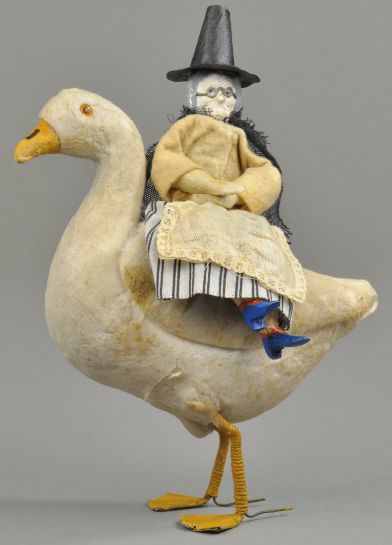 GERMAN WITCH ON GOOSE CANDY CONTAINER: Very nice spun cotton goose with witch on Mother Goose type figure riding side saddle, of note are her bright blue wooden shoes, wearing decorative cloth, goose wing lifts up to place candy in body. 7