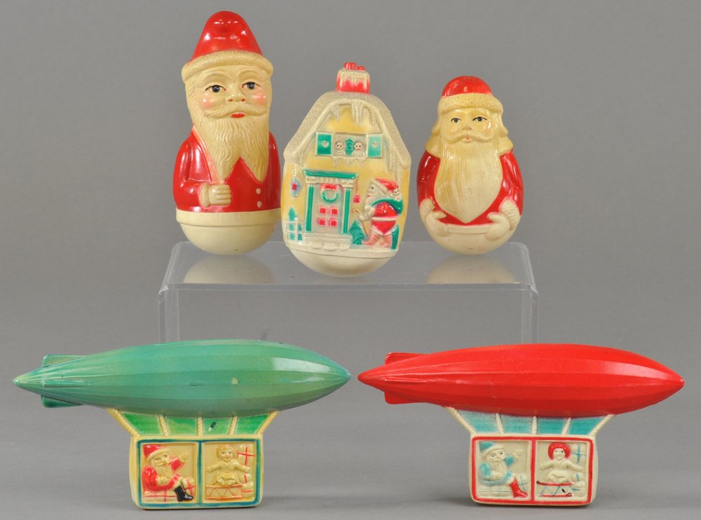 ATTRACTIVE ASSORTMENT OF CHRISTMAS CELLULOIDS: Nice mix consisting of two Santa airships, Santa house, and two Santa roly polys. 3" to 5 1/2" l. Ex. Tom Fox Collection.