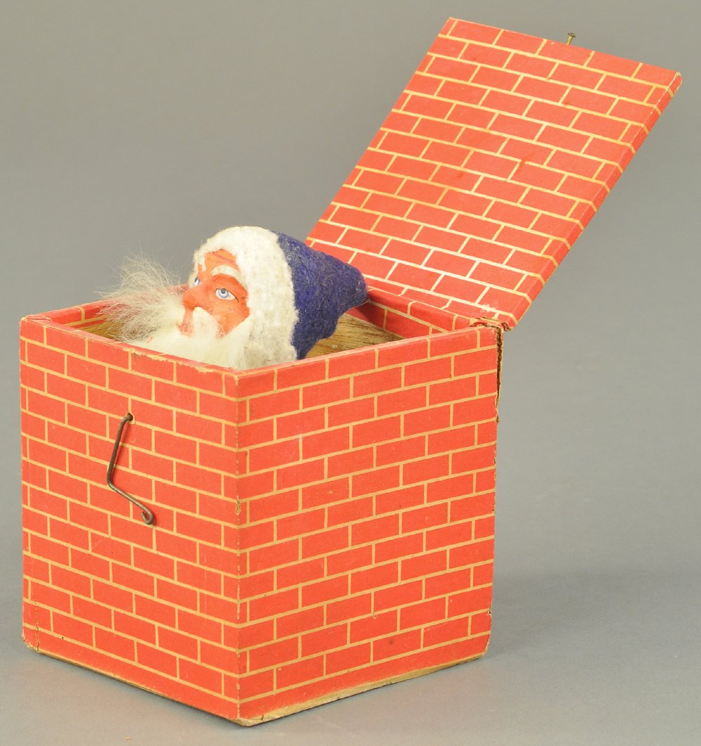 GERMAN SQUEAKER SANTA IN A BOX: Jack-in-the-box squeaker toy with paper bellows in good working condition, Santa has composition head, rabbit fur beard and blue hood. 4 1/2" l. Ex. Tom Fox Collection.