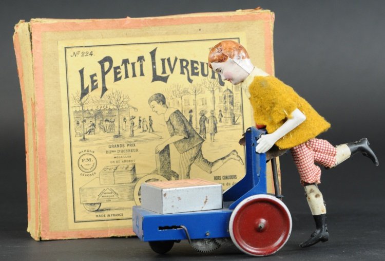 DELIVERY BOY WITH WAGON: Fernand Martin, France, boxed example, depicts cloth dressed boy with tin body pushing blue wagon holding box, disc wheels, clockwork driven. 7" h.