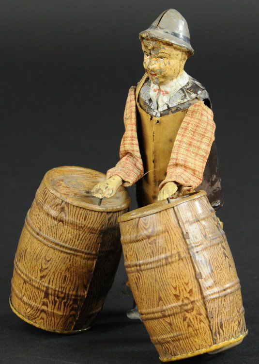 FERNAND MARTIN BARREL ROLLER: Painted and lithographed tin, partially cloth dressed man with hidden clockwork mechanism, walks along seemingly rolling two barrels, amusing action. 7 1/2" h.