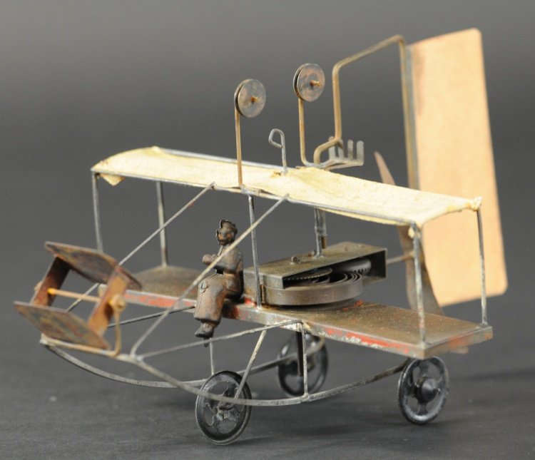 PUSHER BI-PLANE: Germany, based on early Wright Bros. design, hand painted tin, traces of red trim, seated lithographed pilot, canvas top wing, rear paper rudder, pulleys allow string travel, clockwork activated. 10" 