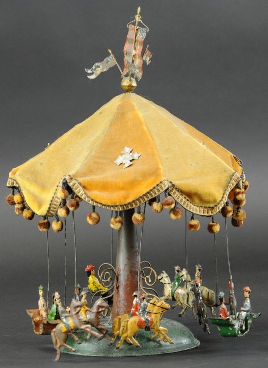 MERRY-GO-ROUND: Germany, hand painted tin, ornate tower support with canopy top, four gondolas with seated figures and eight carousel horses and seats with figures, clockwork driven. 16" h.