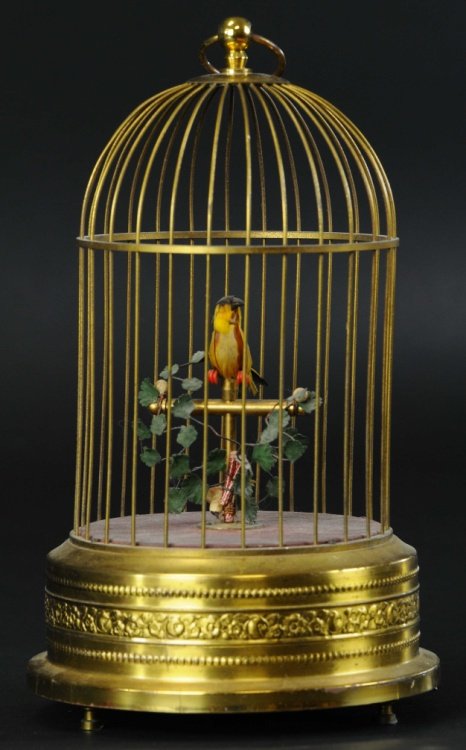 MECHANICAL BIRD CAGE: Circular base similar to many French bird cage examples with internal clockwork mechanism allowing chirping motions and body shifting, gold circular base, yellow feathered bird.