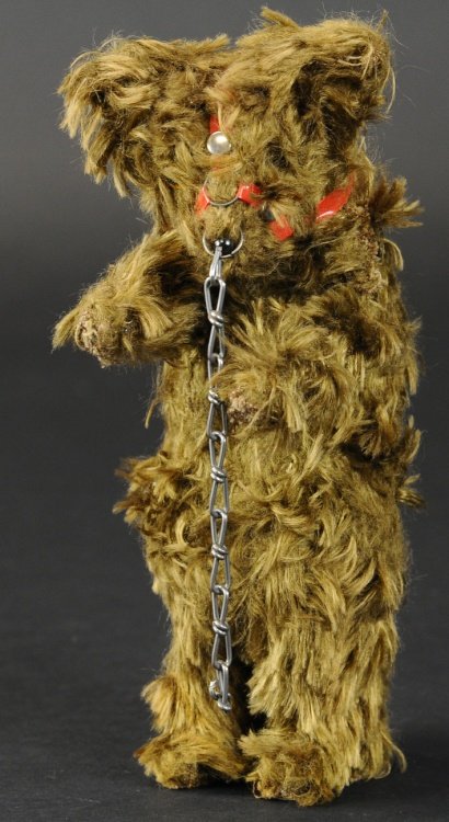 MECHANICAL PERFORMING BEAR: Mohair covered body with muzzle and training chain attached, stands tall with arms outstretched, fur shows some matting from age, clockwork activated. 8 3/4" h.