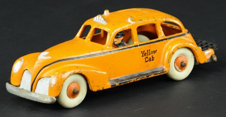 HUBLEY YELLOW CAB: C. 1940, cast iron, painted in bright orange color, decal on side door reads 'Yellow Cab,' seated driver painted in black, white rubber tires on orange wooden hubs, folding luggage rack on trunk. 8 1/