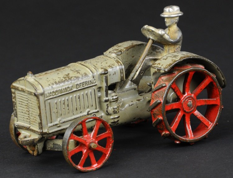 ARCADE McCORMICK DEERING 10-20 TRACTOR: Cast iron, painted in grey overall, seated nickel driver, spoke wheels, red disc wheels, embossed hood reads 'McCormick Deering.' 7" l.