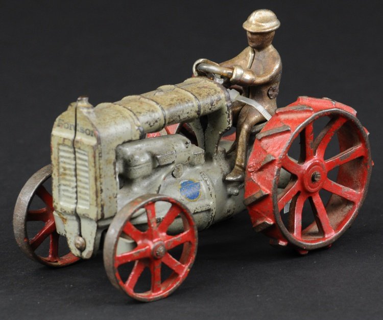 ARCADE FORDSON TRACTOR: Cast iron, painted in grey with gold highlights, red spoke wheels, seated driver, made in late 20's and early 30's, a very popular toy. 5 1/2" l.