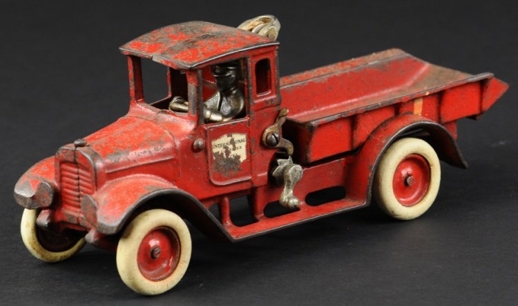 IH BABY DUMP TRUCK: Arcade, cast iron, painted in red overall, IH decals on doors, nickel lift bar on front of bed, disc wheels have painted centers, white rubber tires. 10 1/2" l.
