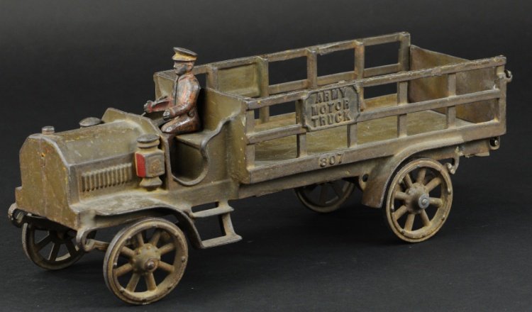 JONES & BIXLER ARMY MOTOR TRUCK: Large scale, cast iron, open stake body, painted in olive green overall, embossed sides read 'Army Motor Truck,' seated driver, spoke wheels and cast head lamps. 14 3/4" l.