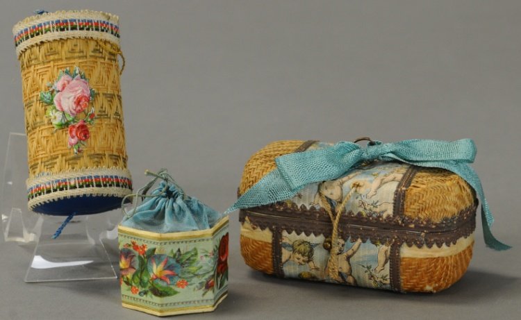 THREE DECORATIVE CANDY CONTAINERS: Rectangular box with scene of cherubs on woven straw, cylindrical box with woven straw and blue silk covering, yellow silk bag inside, six sided mini box, floral print, blue silk draw string top. 1 1/