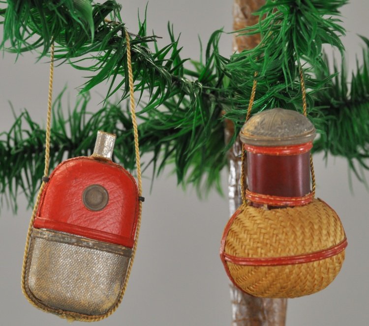 WHISKEY FLASK AND DEMI JOHN CANDY CONTAINER: Two German Dresdens; a red and silver pocket flask and a demi john in a wicker basket, both open at the top for candy retrieval. Each 2". Ex. Tom Fox Collection