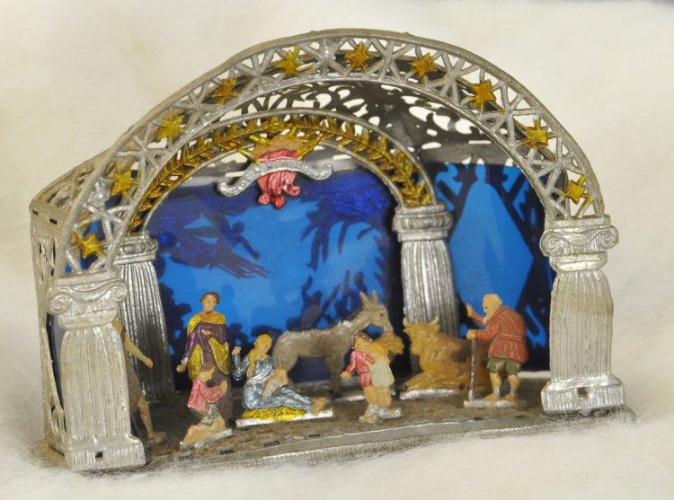 WONDERFUL GERMAN SEBNITZ CRECHE: A magnificent, painstakingly hand crafted nativity, done in soft metal with a blue pressed gelatin back drop showing shepherds with their flock and angels overhead. 4". Ex. Tom Fox Collection