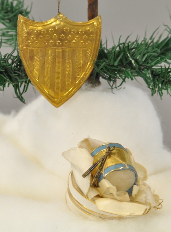 TWO PATRIOTIC DRESDEN ORNAMENTS: Gold puffed shield ornament with blue and gold drum over silk petals upon a white candy box, drum has tiny round sticks attached. 2" x 2". Ex. Tom Fox Collection