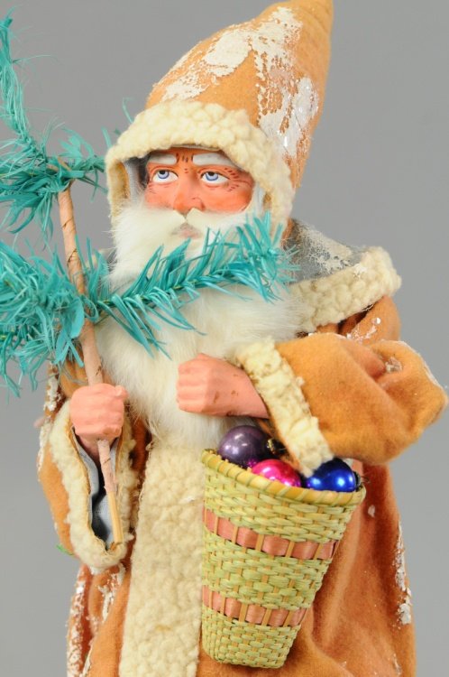 TALL FATHER CHRISTMAS CANDY CONTAINER: Germany, an impressive example, this early Belsnickle is dressed in a long red robe trimmed in white, a stern looking composition face with rabbit fur beard, a basket of glass balls on one arm, a mult