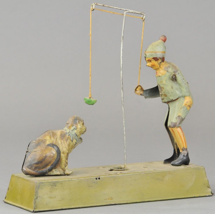 BOY & PERFORMING DOG TOY: Germany, lithographed tin, depicts standing boy figure seemingly teasing dog with ball on string. 9 1/4" l.