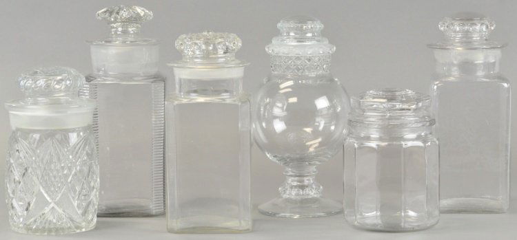 SIX CANDY SHOW JARS & TOBACCO JAR: A small Dakota globe jar, two pressed glass display jars and three square store jars, all with ground glass lids and multi sided tobacco storage jar. 8" to 12" h.