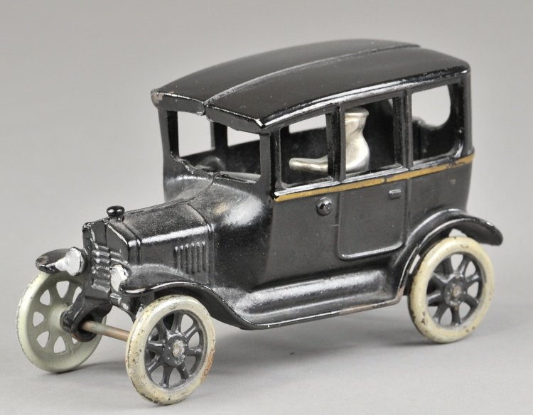 FORD TUDOR (CENTER DOOR) SEDAN: Arcade, cast iron, painted in black overall with gold stripe, includes seated nickel driver, spoke wheels, done in black and white. 6 1/2" l.