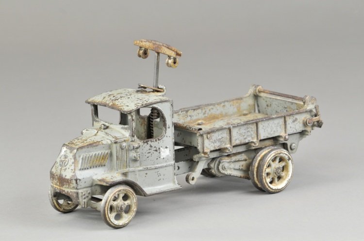 ARCADE MACK DUMP TRUCK: Cast iron, painted in grey overall, 'T' bar on back of cab for unloading, opening tailgate, seated driver, Mack logo on front, painted spoke wheels, dual on rear. 12" l.
