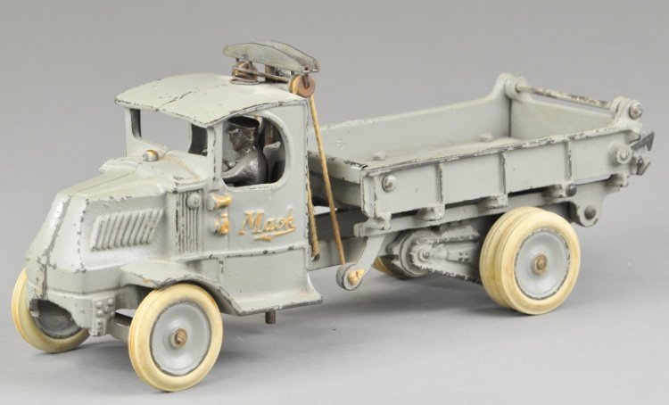 ARCADE MACK DUMP TRUCK: Cast iron, painted in grey overall, 'T' bar on back of cab for unloading, opening tailgate, seated driver, Mack embossed on side, rubber tires and painted disc wheels, dual on rear. 12" l.
