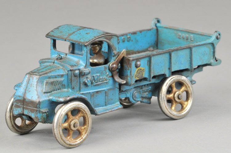 ARCADE MACK DUMP TRUCK: Cast iron, mid size, painted in blue overall, body tilts for unloading, nickel spoke wheels, seated driver, lever on side. 8 1/2" l.