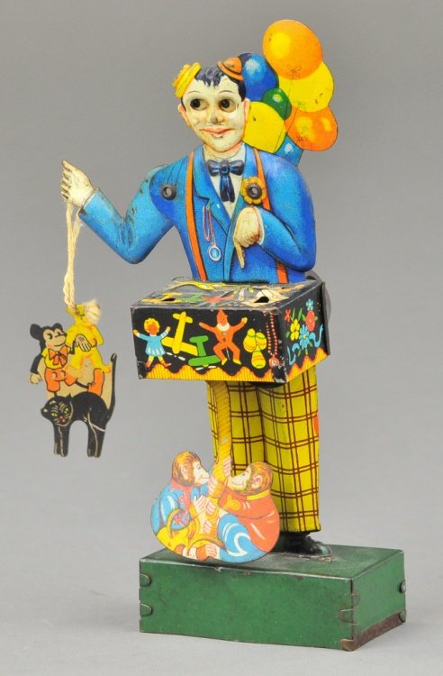 KELLERMANN BALLOON VENDOR: Germany, lithographed tin, die cut figure holds small Mickey and toys die cut in hand by string, clockwork activates pair of die cut monkeys at feet, very popular and colorful toy. 6 1/2" h.