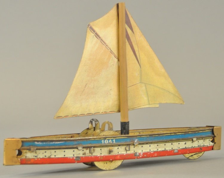 HESS SAILBOAT: Germany, lithographed tin hull, lithographed cardboard sail, flywheel driven, wheels concealed in deck. 6 3/4" l.