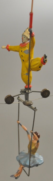 TIGHTROPE AND CIRCUS PERFORMER: String toy features clown on tightrope, made by hanging a string with seated lady on swing for balance, hand painted lead figures. 7" h.