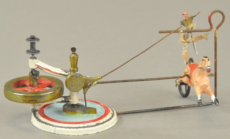 BRITAIN BARE BACK RIDER TOY: England, circa 1906, hand painted horse with rider is set in circular motion via inertia wheel, allowing lady rider to seemingly leap over the bar hurdle and settle back down on the horse. 5" radius
