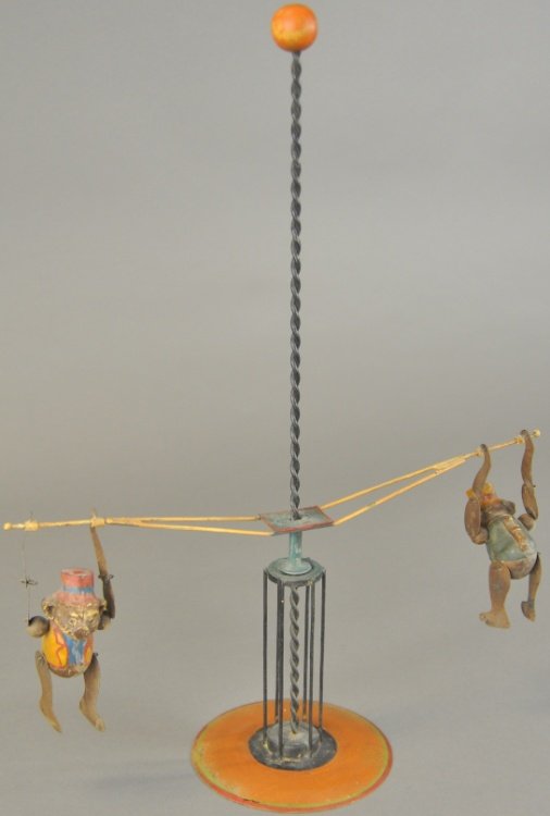 TWO MONKEYS GRAVITY SPRIAL TOY: Features two figures at each end of poles able to traverse down center spiral box on painted base, made of mixed medium. 17 1/2" h.