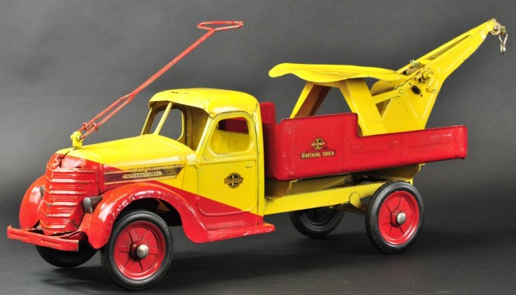 BUDDY 'L' DELUXE RIDER WRECKING TRUCK: c. 1938, pressed steel, two-tone slant color design of red and yellow, open service body contains crane on swivel base, rubber tires, spoke wheels, pull and ride handle. 33" l.