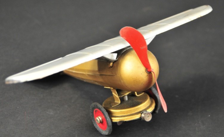 KINGSBURY "TRANSATLANTIC" MONOPLANE: c. 1927, pressed steel, painted in silver wings and gold fuselage, clockwork motor, rubber tires are flattened hard rubber, red disc wheels, single prop. 10" wingspan.
