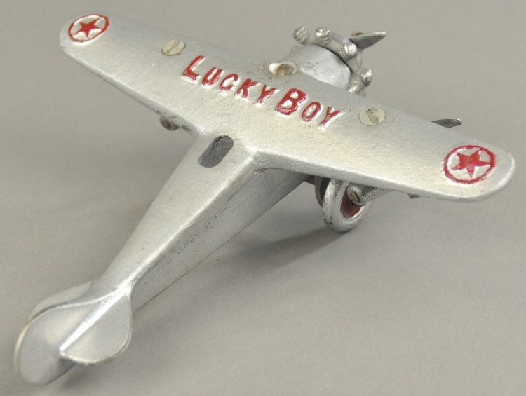 DENT LUCKY BOY TRIMOTOR AIRPLANE: Cast iron, painted in silver overall with red highlights on embossed wings, disc wheels, features three nickel props. 7 1/4" wingspan.