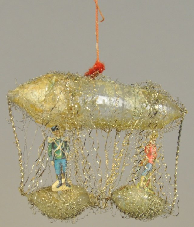 ZEPPELIN WITH TWO BASKETS ORNAMENT: One of the finest examples of wire wrap, blown glass, Christmas tree ornament art, this airship has two suspended baskets with Prussian soldiers. 5 1/2" l.