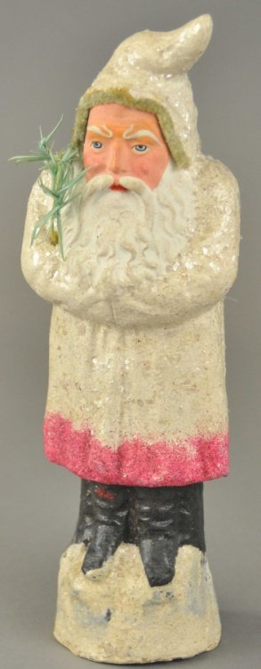 * WHITE ROBE GERMAN BELSNICKLE: Standing on a snow mound, wearing a white robe flecked with mica, pipe cleaner trim around hood, this composition Santa holds a feather tree sprig, good strong detail and colors. 10 1/2" l.