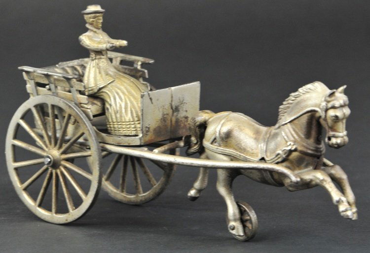 SHIMER ROAD CART: Nickel plated cast iron, solo drawn open cart features seated lady driver at embossed and railed open seat, spoke wheels. 10" l.
