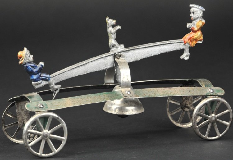 WATROUS BOY AND GIRL ON SEESAW BELL TOY: Cast iron and tin strap platform, depicts boy and girl at each end with standing dog at center, articulated action allows up and down motions as center bell rings. 9 1/4" l.