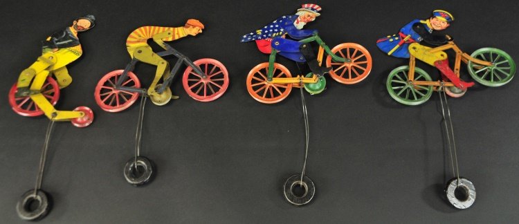 GROUPING OF BICYCLIST STRING TOYS: A. C. Gilbert, lithographed tin, familiar whimsical die-cuts of bicyclist string toys, includes: Turtle Neck rider, Keystone Cop, Hobo, and Uncle Sam examples, all able to traverse along string with w