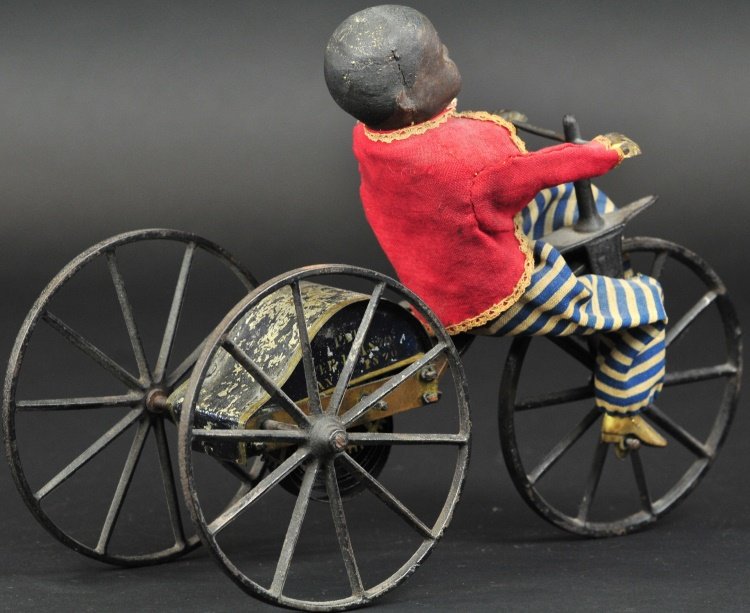 BOY ON VELOCIPEDE: Stevens & Brown, Patent by Arthur M. Allen 1870, popular clockwork toy, hand painted tin and cast iron, black figure version, seated boy wears cloth outfit, made of hand painted composition with brass
