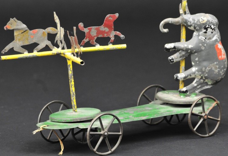 CIRCUS ANIMALS ON PLATFORM: Attributed to Merriam, depicts hand painted tin elephant standing on swivel platform while four die-cut horses appear on elevated pole prop, each able to revolve on platform when pulled along. 8 3/4" 