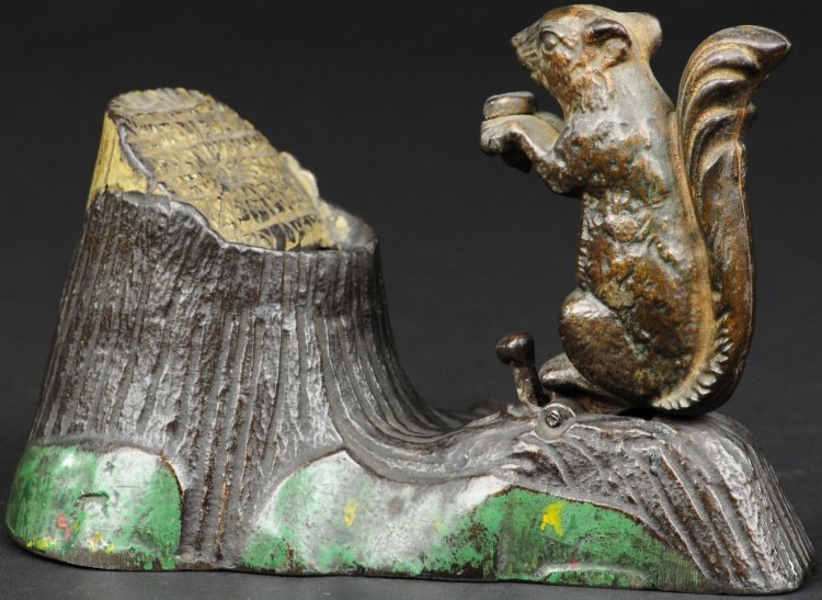 SQUIRREL & TREE STUMP MECHANICAL BANK: Mechanical Novelty Works, designed by Robert E. Turnbull, patented 1881, cast iron and hand painted, place a coin in the squirrel's forepaws, touch the spring and squirrel bounds forward and throws th
