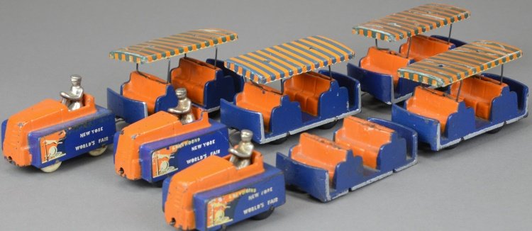 ARCADE 1939 WORLD'S FAIR TRACTOR TRAIN: Classic tram car with engine and five cars, full decals, painted in familiar orange and blue overall, lithographed tin roofs, nickel seated drivers. Cars 4 1/2" l.
