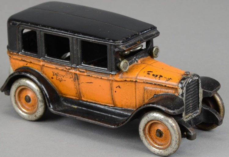 ARCADE FLAT TOP TAXI: Cast iron taxi done in orange and black, features nickel lights and disc wheels with painted centers, spare on rear, stenciled, "Yellow Cab" on sides, seated driver. 8" l.