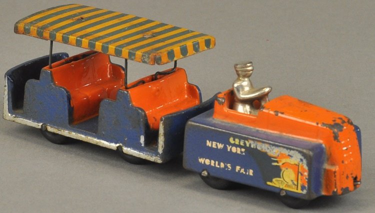 ARCADE 1939 NEW YORK WORLD'S FAIR TRACTOR TRAIN: Arcade classic tram car with engine and cars, full decals, painted in familiar orange and blue overall, lithographed tin roofs, nickel seated driver. 11" l.