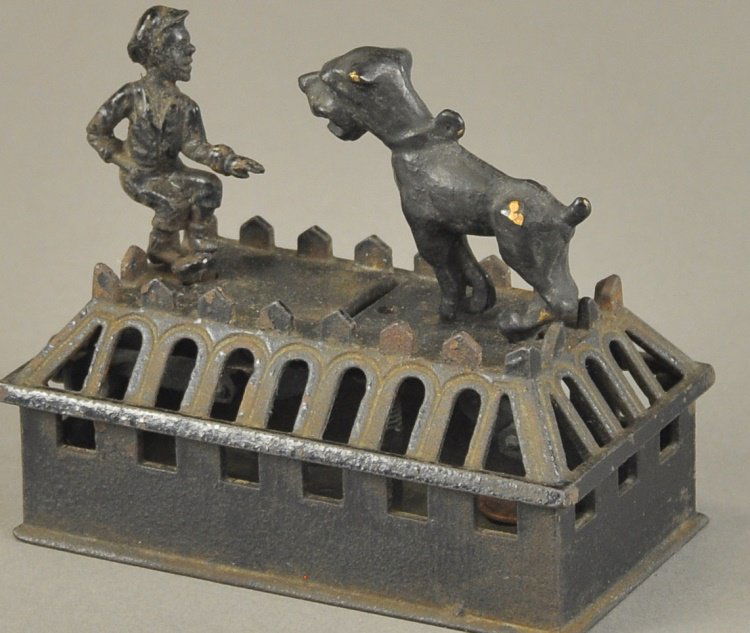 BOY AND BULL DOG MECHANICAL BANK: H. L. Judd Mfg. Co., Wallingford, Connecticut, circa 1870, insert a coin in slot, pulling lever causes the boy to lean forward as if to push the coin into the bank with his outstretched hand. The dog
