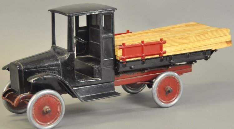 BUDDY 'L' LUMBER TRUCK: c. 1920's, pressed steel, cab done in black, low sided cargo bed, removable stakes, disc wheels, carries load of timber. 24" l.