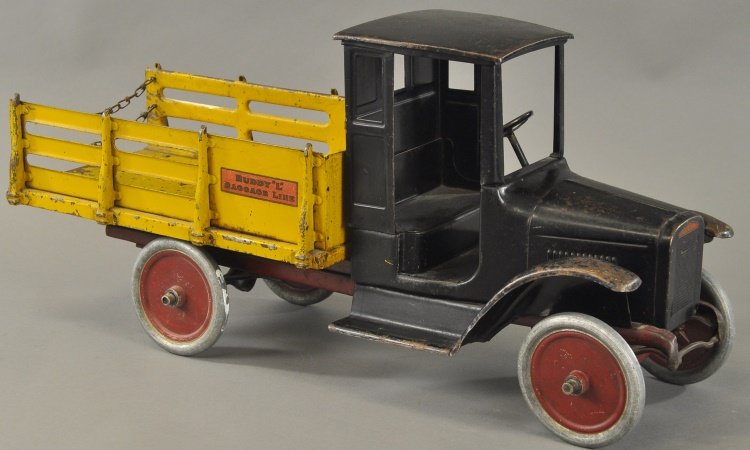 BUDDY 'L' BAGGAGE LINE TRUCK: c. 1926, pressed steel, enclosed black cab, open yellow stake side body, chained tailgate, aluminum disc wheels, decals on sides read "Buddy L Baggage Line" 26" l.