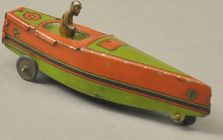 SPEED BOAT PENNY TOY: Fischer, lithographed tin, long nose green and red boat with seated driver, wheels allow floor push. 3 7/8" l.